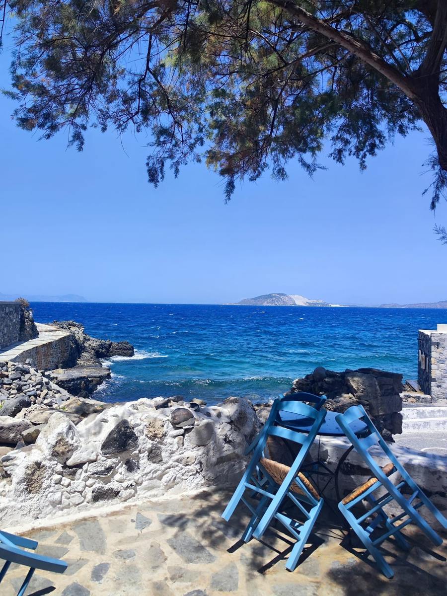 Terrasse mit blauen Stühlen und Blick auf das Meer
